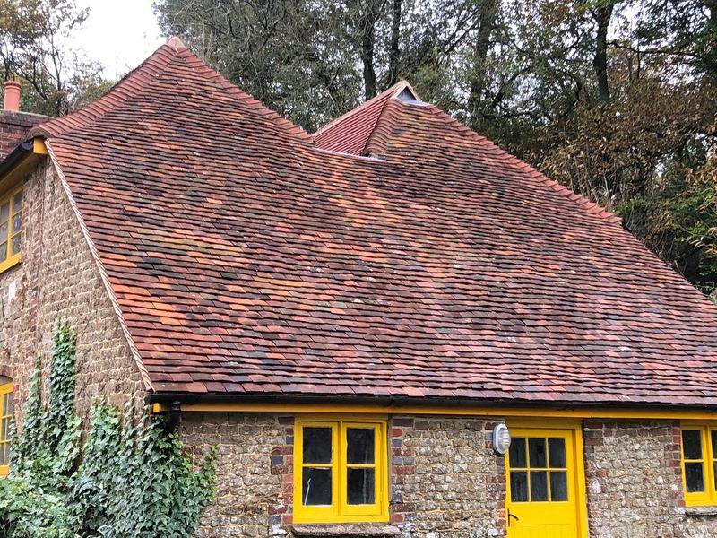 Flint cottage with yellow windows under a reclaimed clay tile roof
