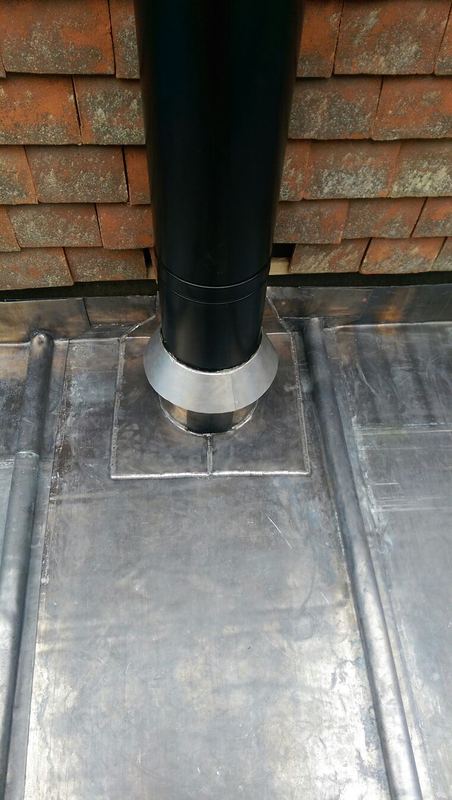 Hand-welded lead flue collar on a leaded flat roof with wood rolls